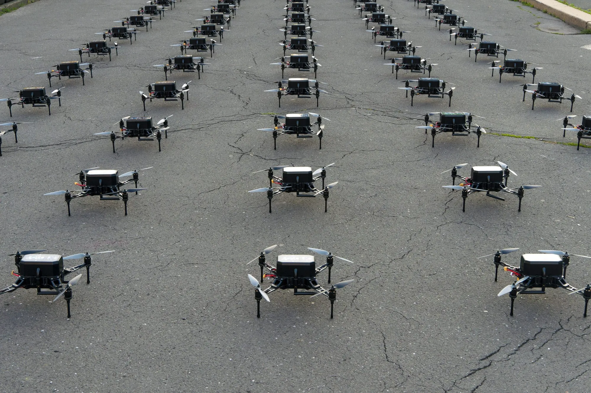 Rows of quadcopter drones arranged on the ground before launch